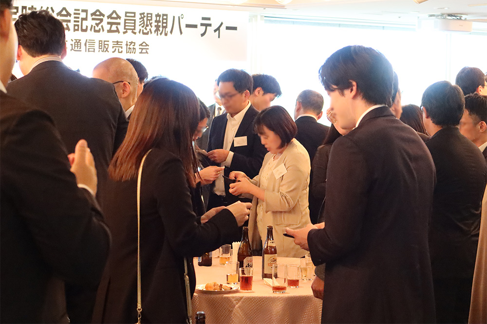 たくさんのビジネスマン。男女が話をしながら名刺を交換している。