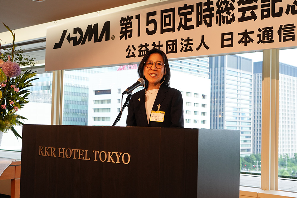 マイクに向かって話すメガネのスーツ姿の女性。台には「KKRHOTELTOKYO」の金色の文字