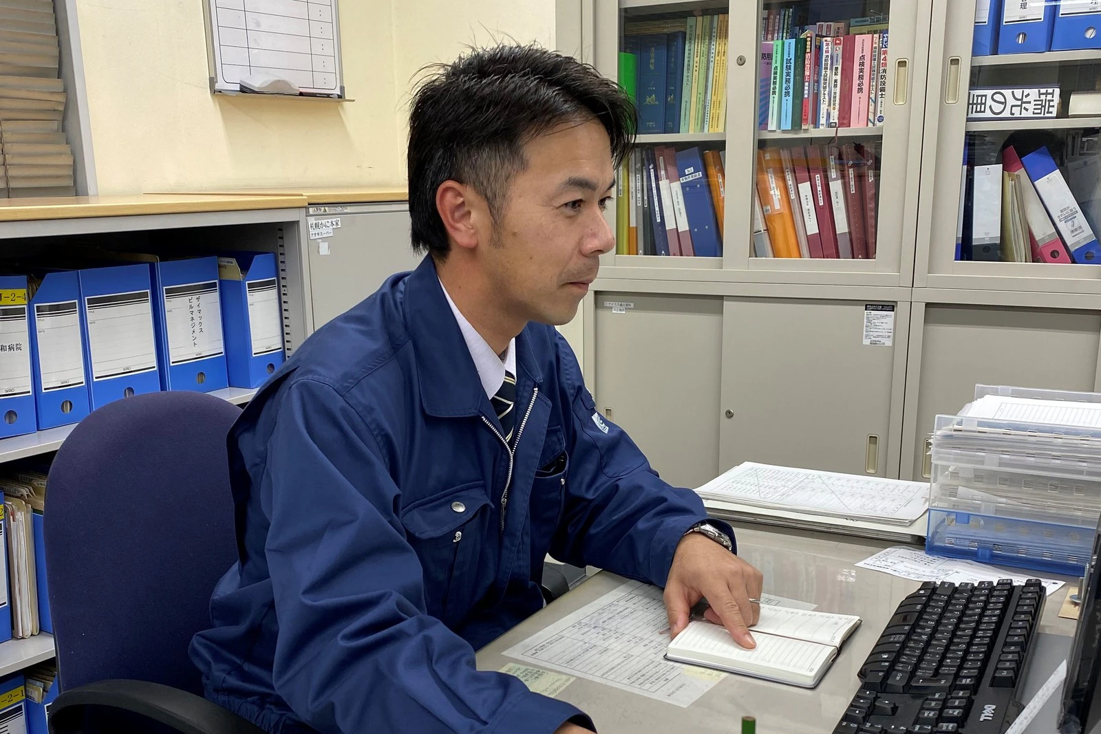 事務所で工事現場の書類に向かう社員