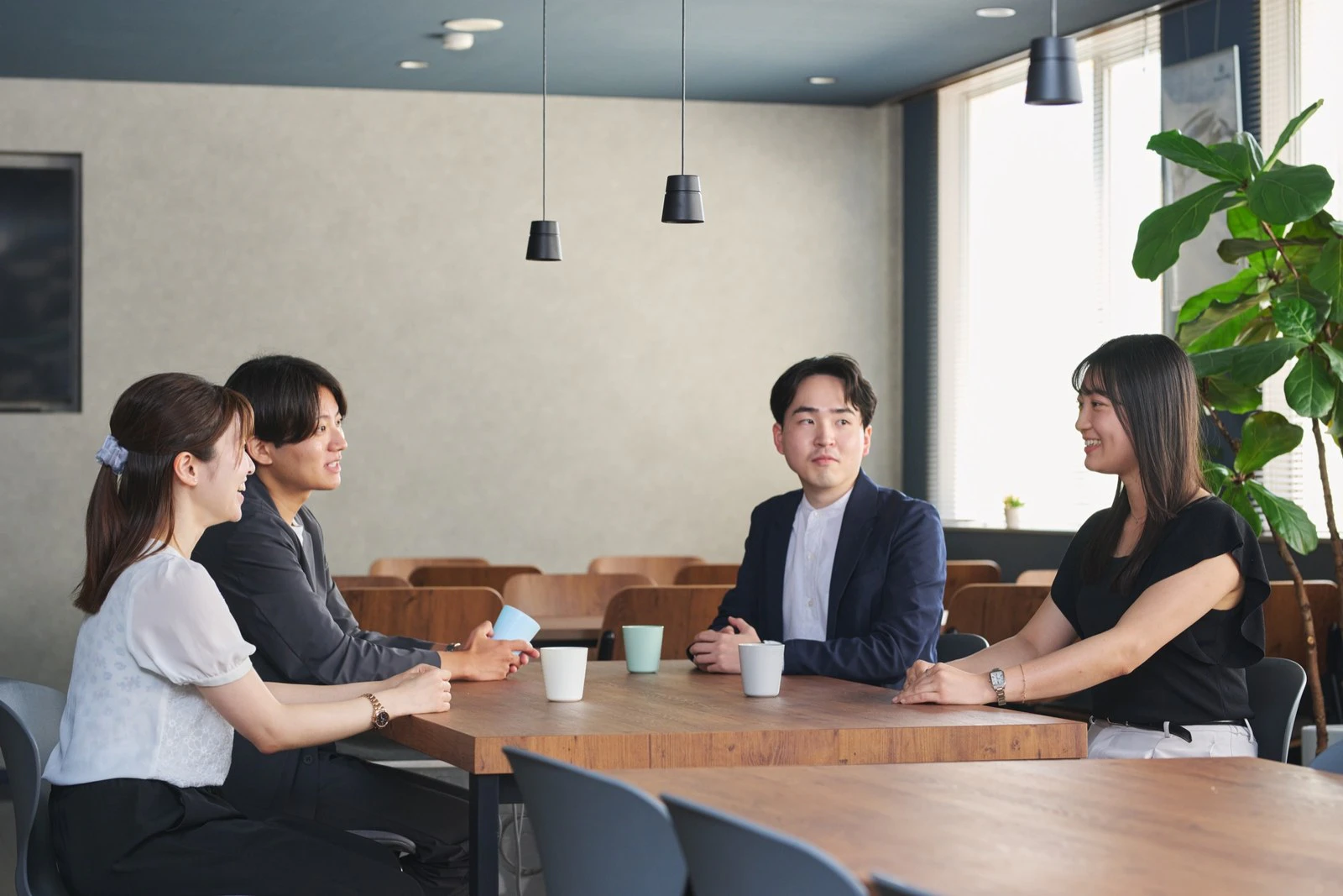 社内の休憩スペースでテーブルを囲み談笑する社員の方々