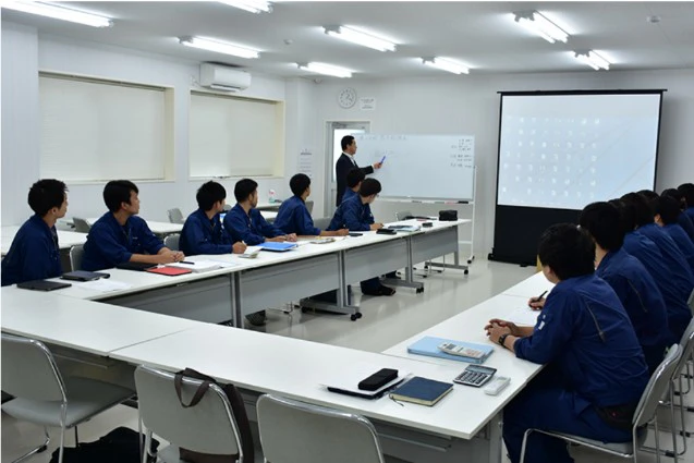 新卒社員向けの研修で、社長がホワイトボードの前で講義をする様子