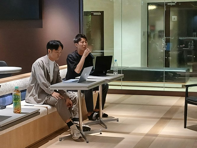 全社ミーティングでマイクを持ち発表を行う役員・発表者