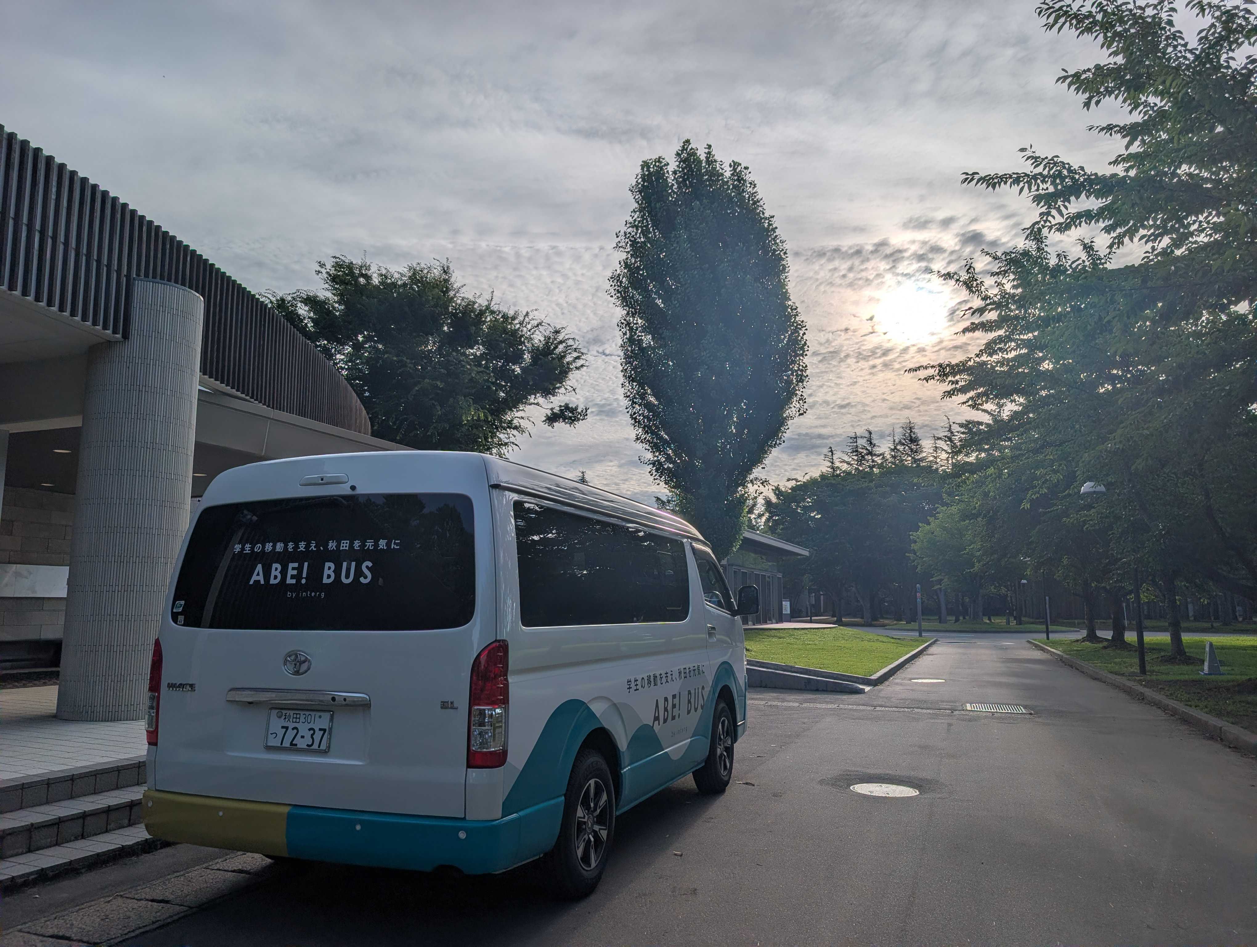 夕暮れ時のAIUキャンパス周辺を走行する「ABE! BUS」の後ろ姿