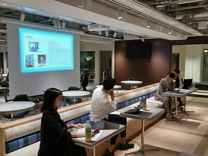 全社ミーティングでスライドを背に自身の経験やミッションを語る代表の那須