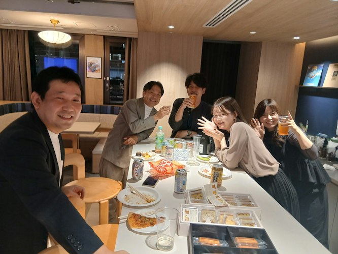 全社ミーティング後の懇親パーティーで料理やドリンクを囲み笑顔で乾杯するメンバーたち