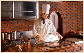 カウンターでシェフが焼き上げるステーキの画像