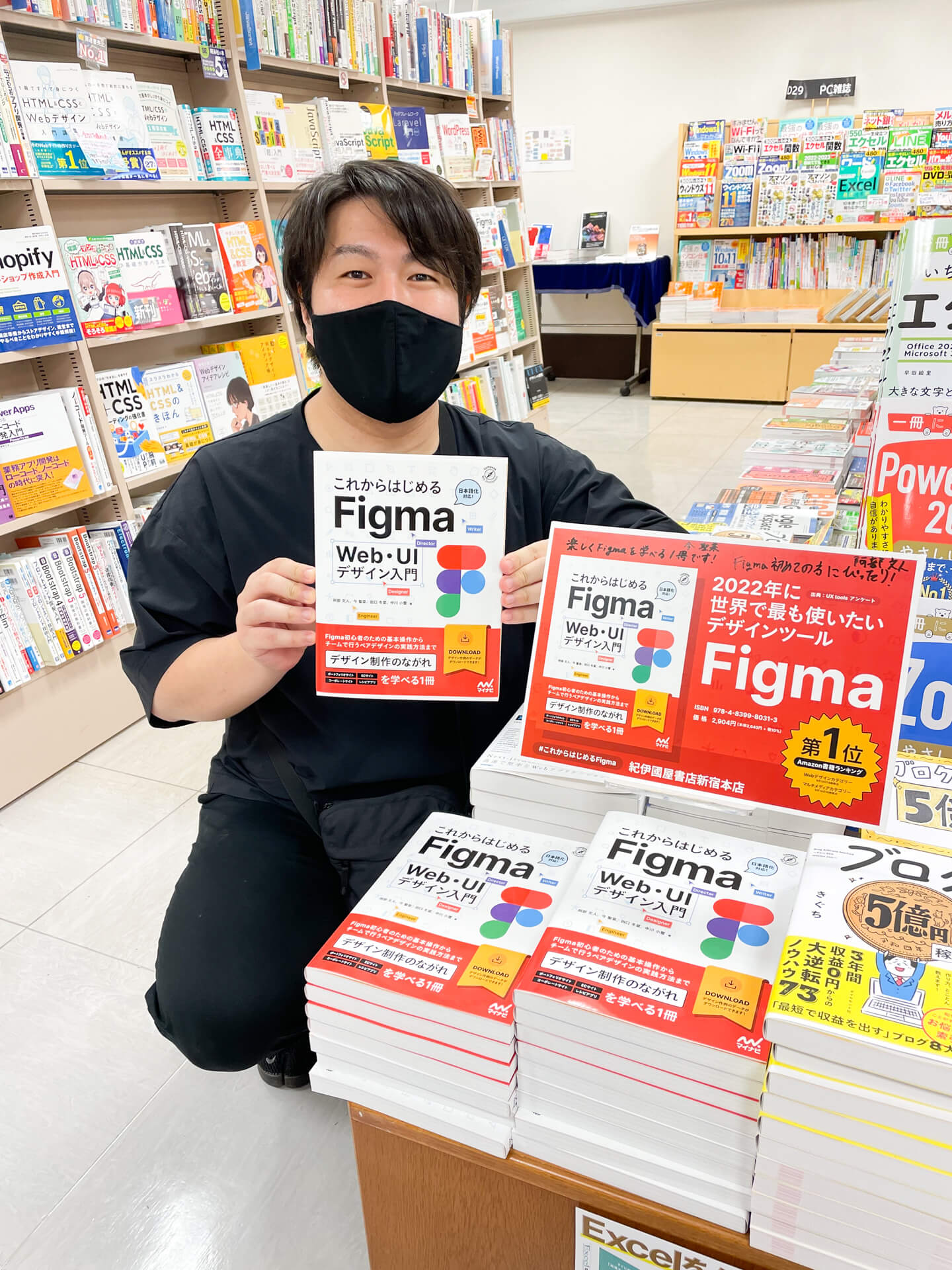 阿部が本を持って書店で写真を撮っている様子