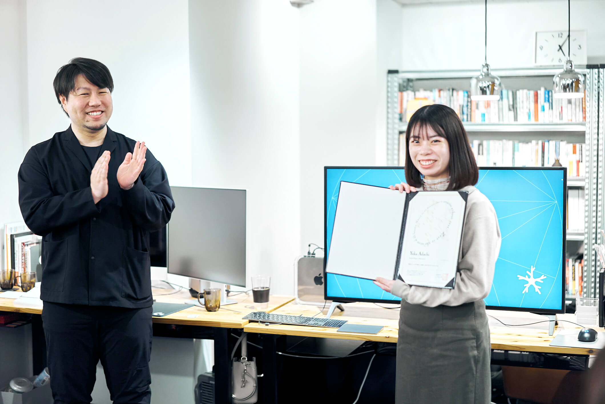 安達友香さんが入社証を持って微笑んでいる写真
