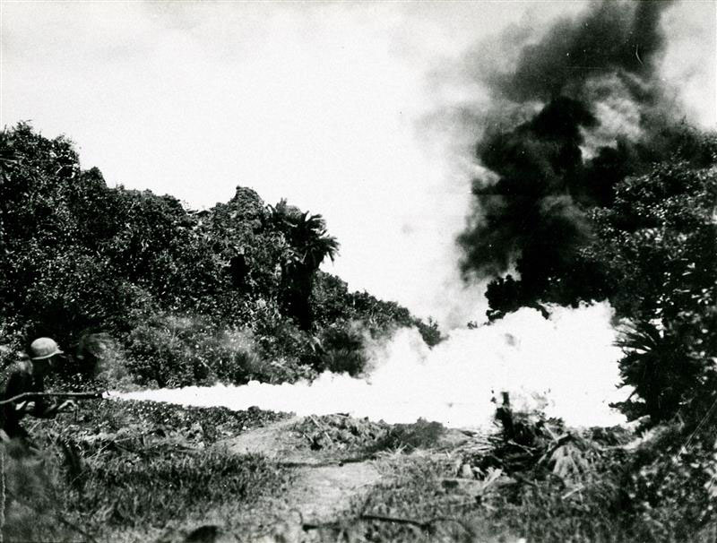 沖縄戦で、やぶに隠れた洞穴を火炎放射器で焼く米海兵隊員。この武器は掃討戦に駆使されたが、民間人も多く犠牲になった＝1945年6月2日撮影
