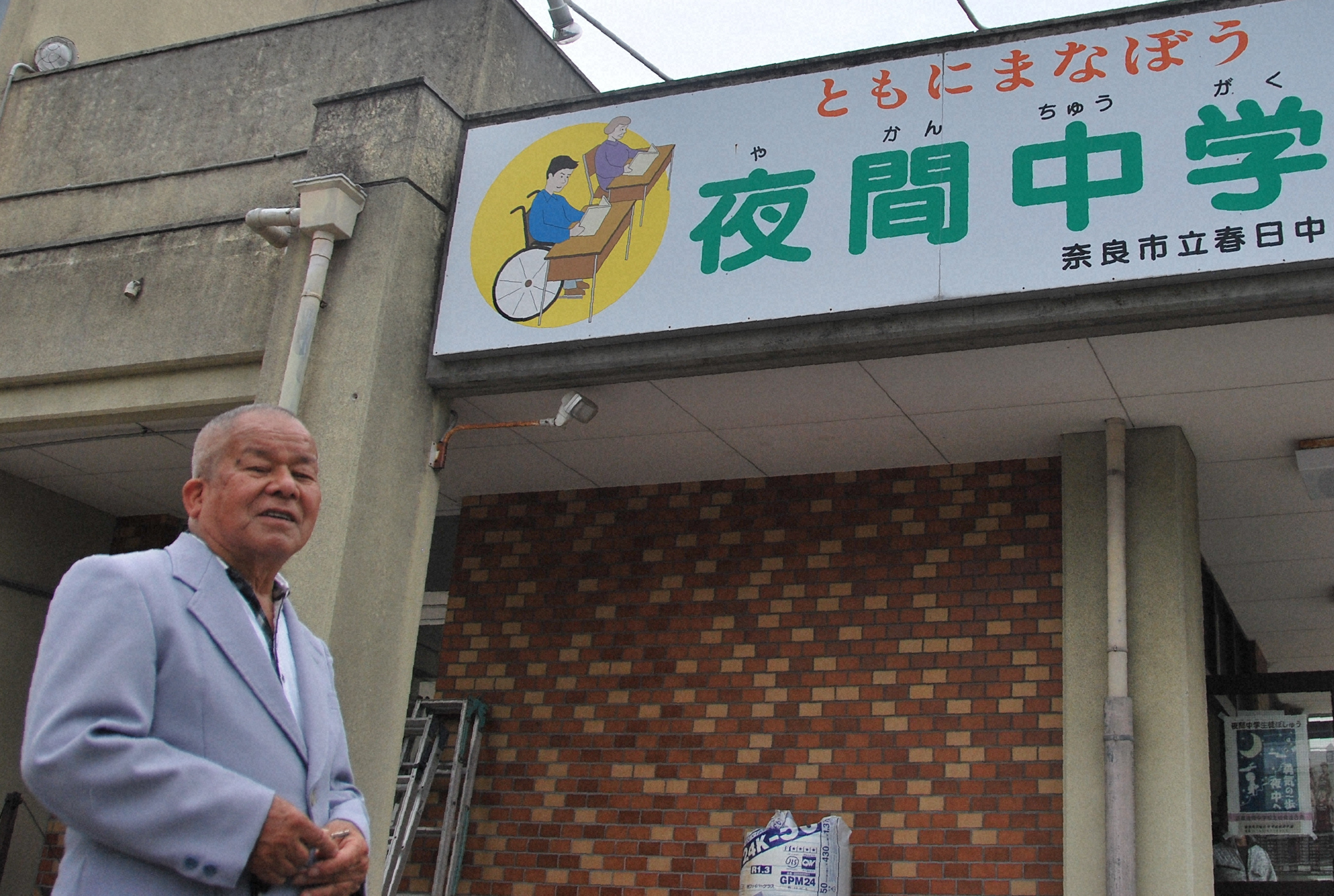 母校の奈良市立春日中の夜間学級の校舎前で笑顔を見せる西畑保さん