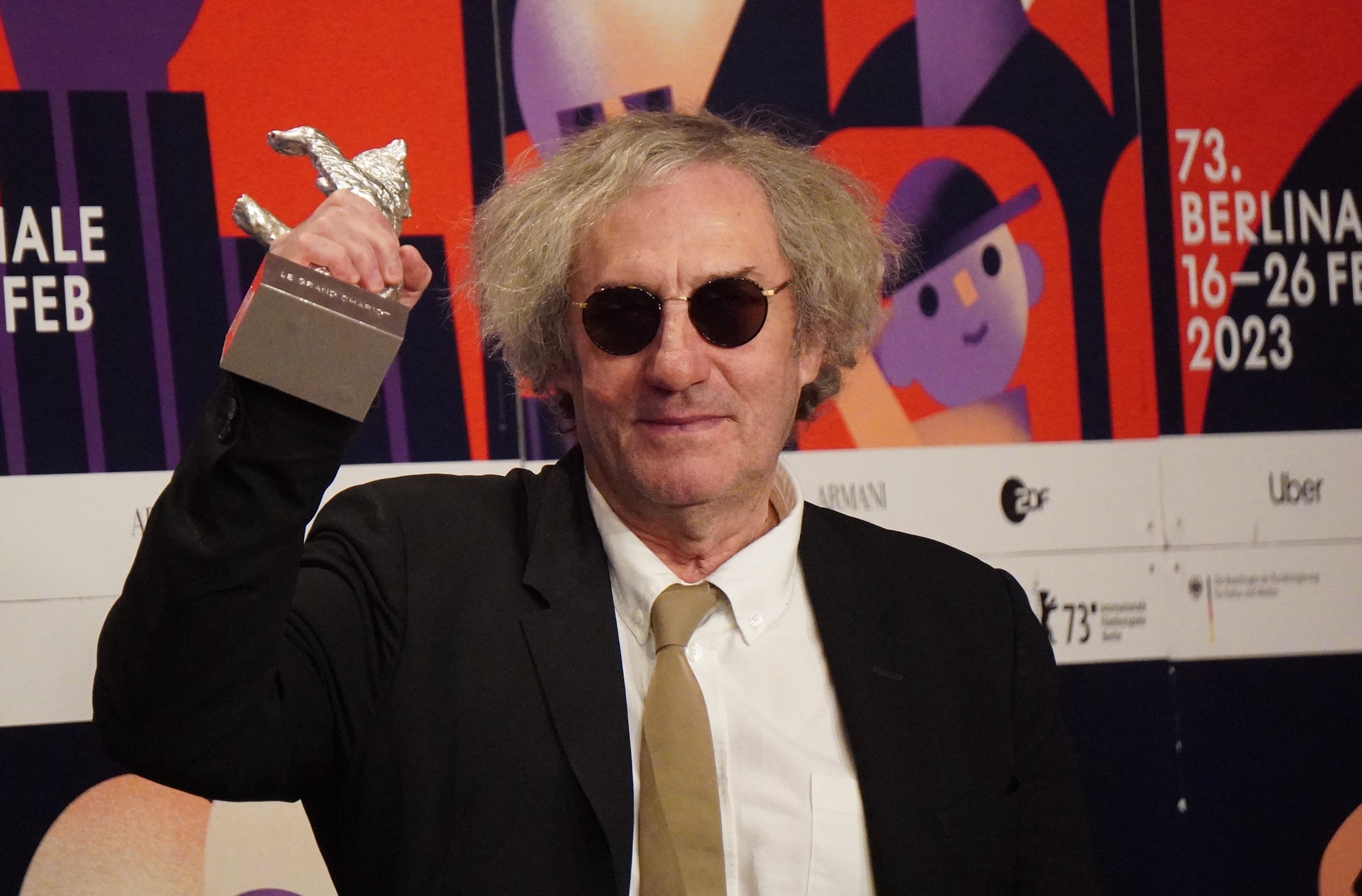 第73回ベルリン国際映画祭で監督賞を受賞し、銀熊のトロフィーを掲げるフィリップ・ガレル監督