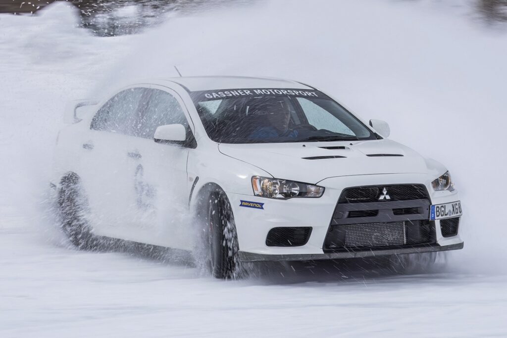 白い車が雪煙を縦ながらドリフトする様子