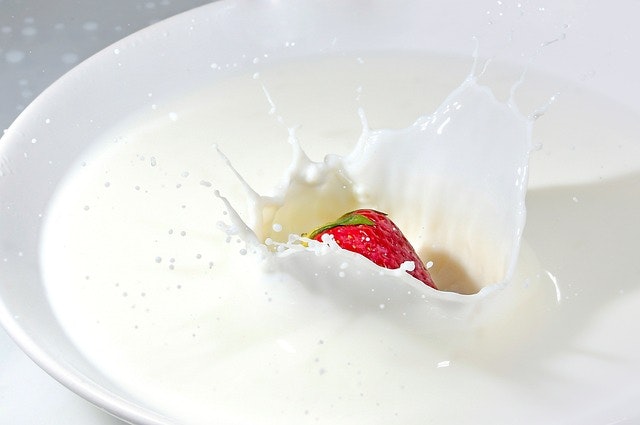 A strawberry dropped in to a bowl of milk