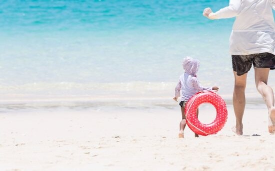 A child with a parent on the beach.