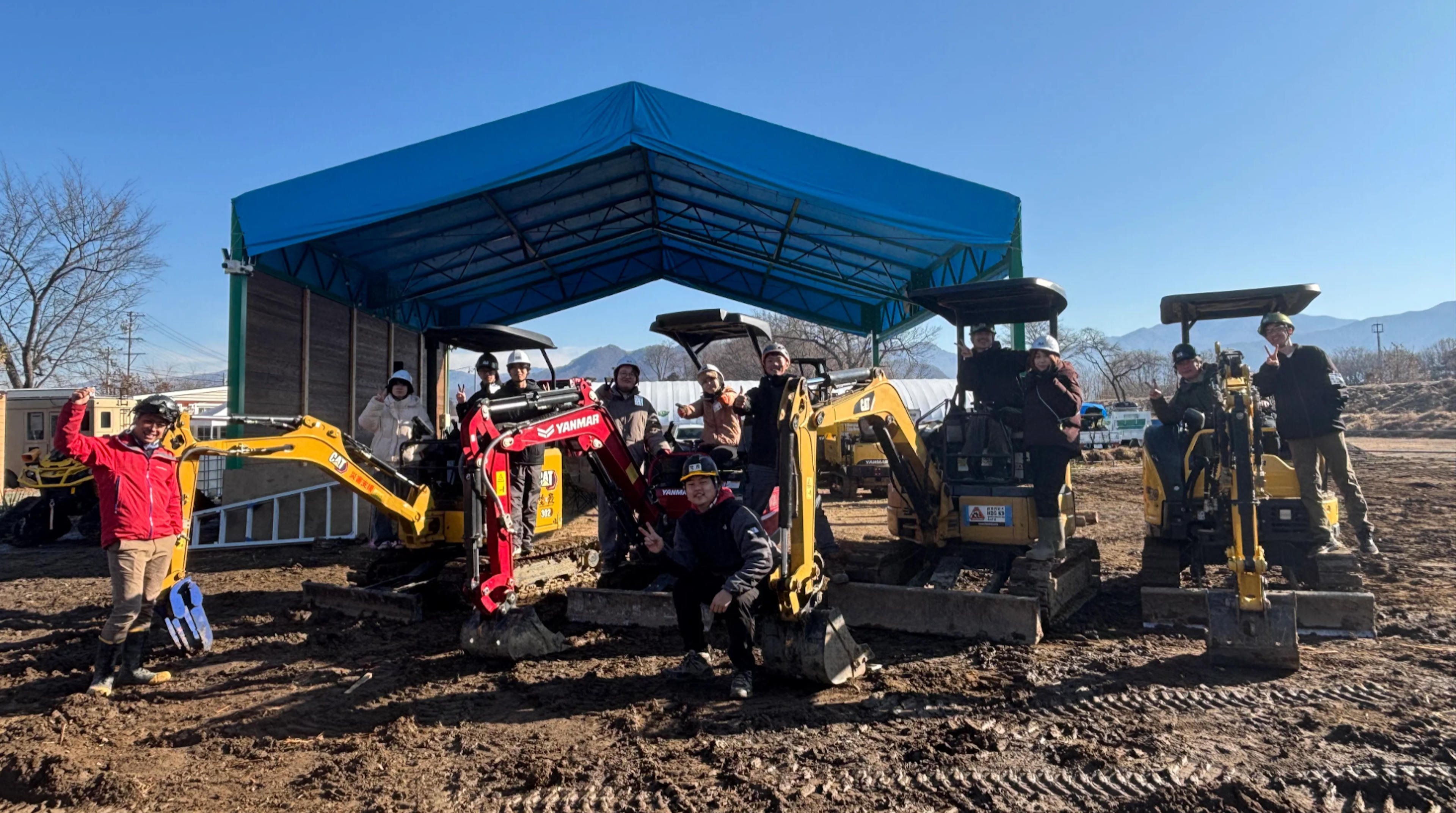 重機を囲んで撮影した、参加学生と講師の方との集合写真