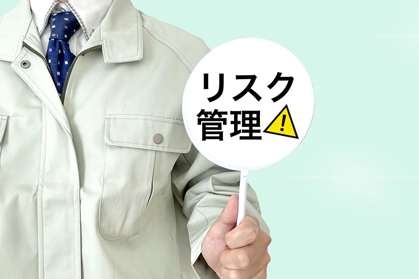 作業着を着た男性が「リスク管理」と書かれたプラカードを手にしている画像