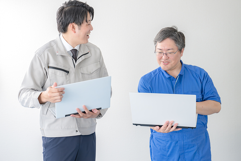 PCを持ちながら話をする作業員の画像