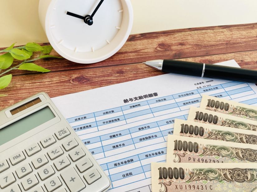 職人の給与計算をイメージさせる、給与支給明細書、現金(1万円札)、電卓、ペン、時計
