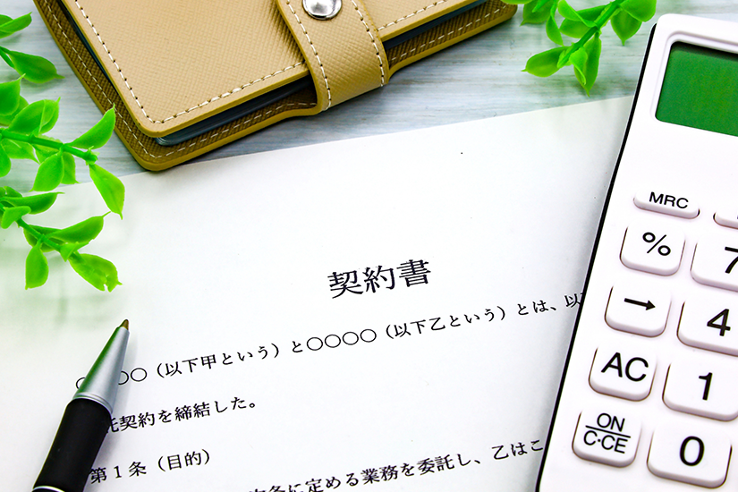 契約書と電卓、財布、ボールペンの画像