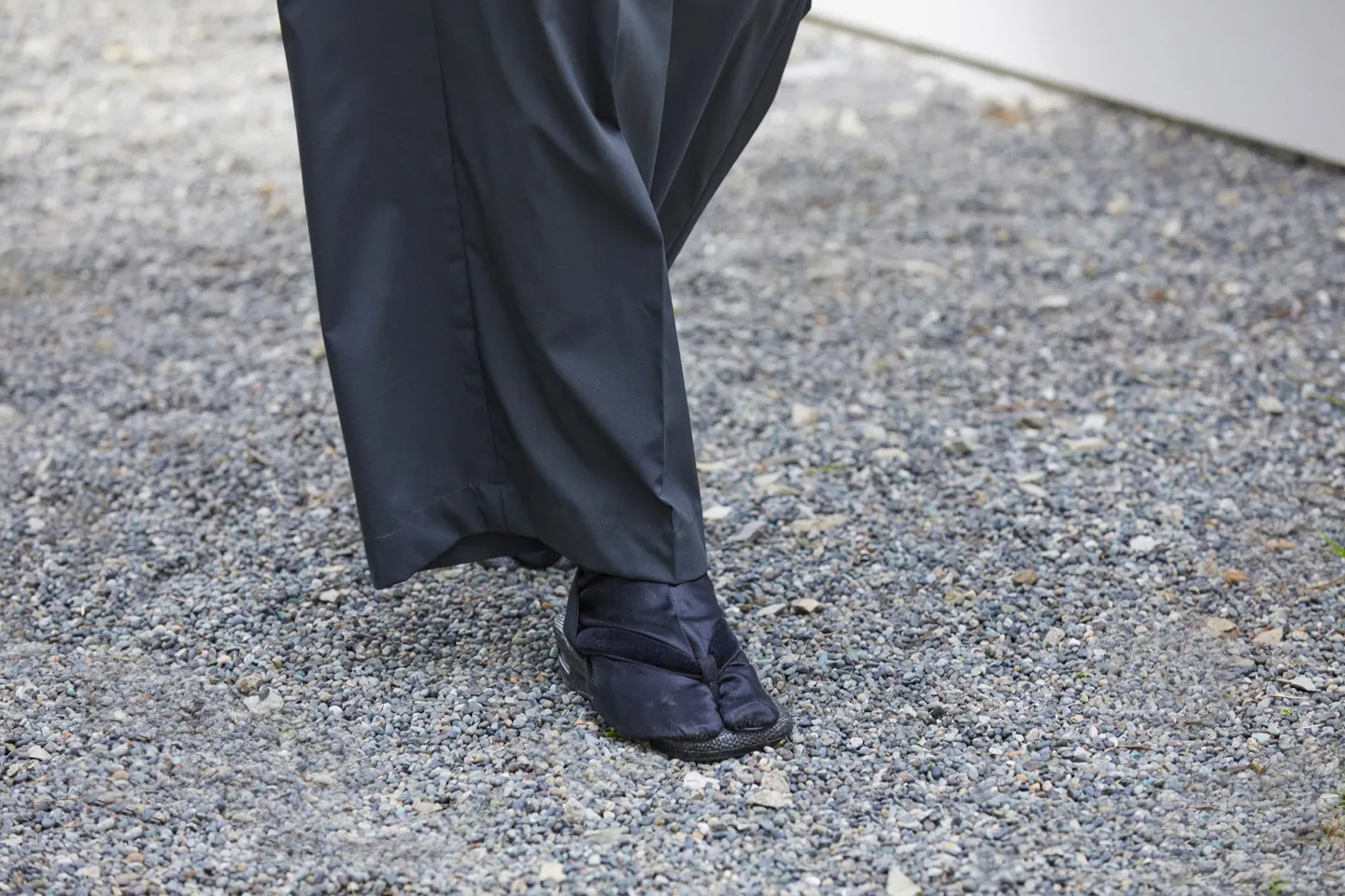 A photo showing the feet of a model walking. The model wears tabi socks and traditional Japanese setta sandals.