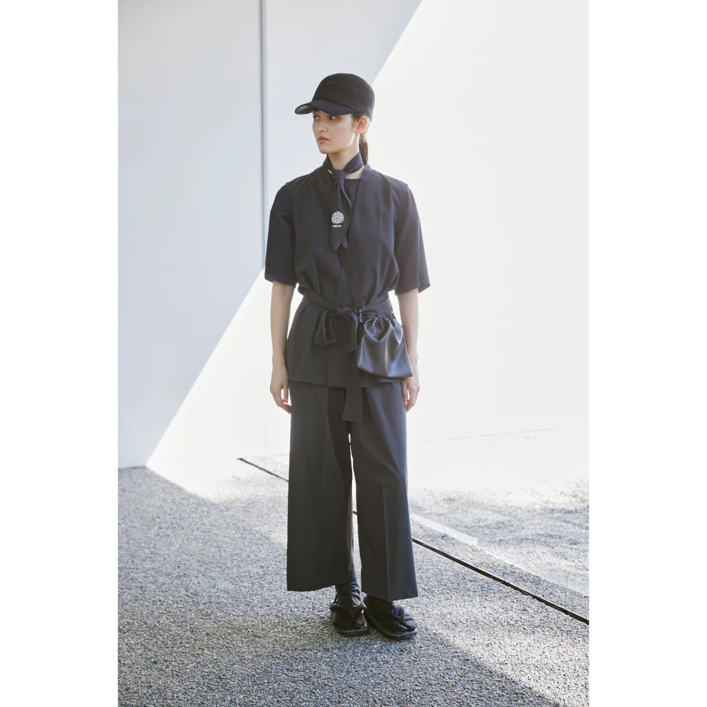 Photo of the uniform for illustration purposes. A female model stands in an abstract space. 