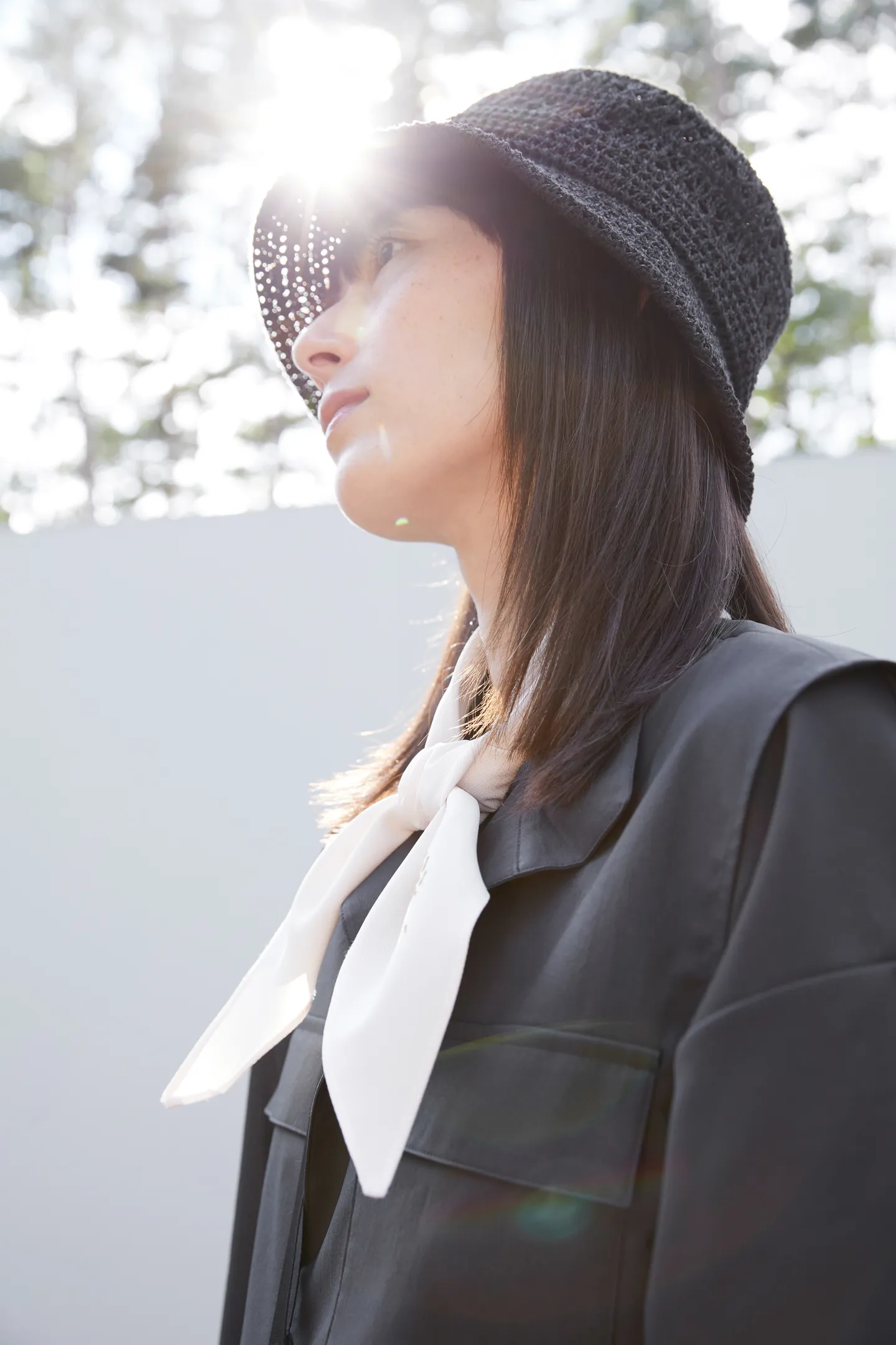 A portrait of the same woman as the previous photo, taken from below and looking up at her. The sun shines through the openwork hat.