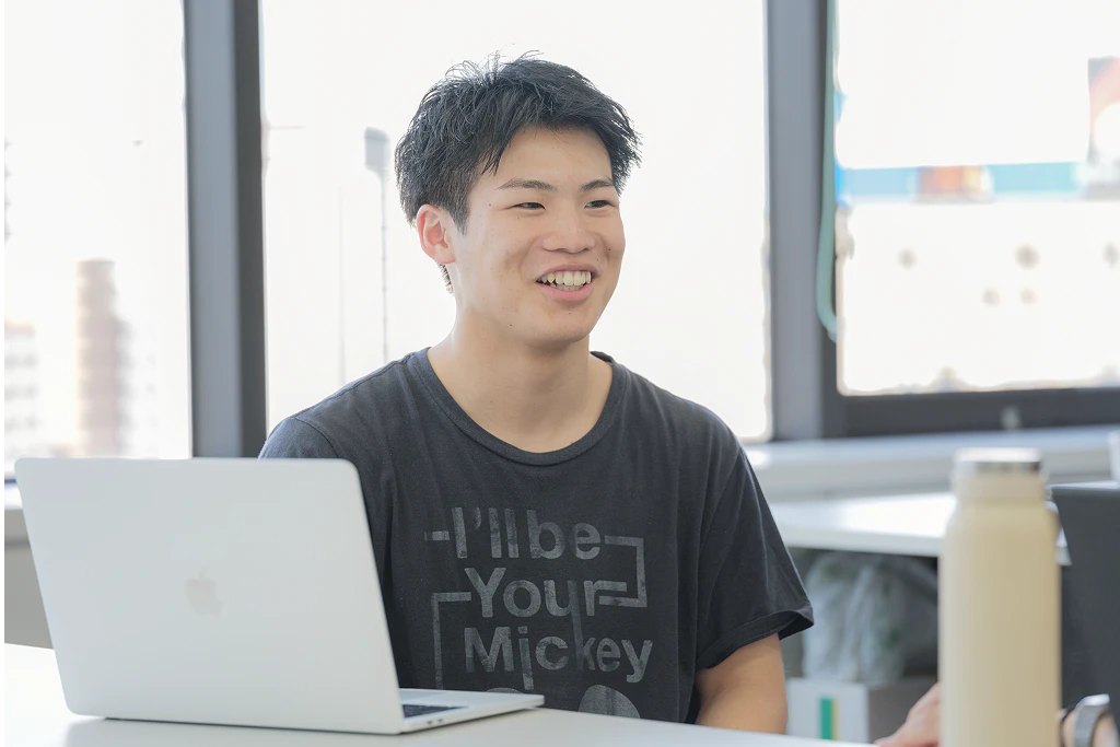 ノートPCを前に、笑顔で話す男性