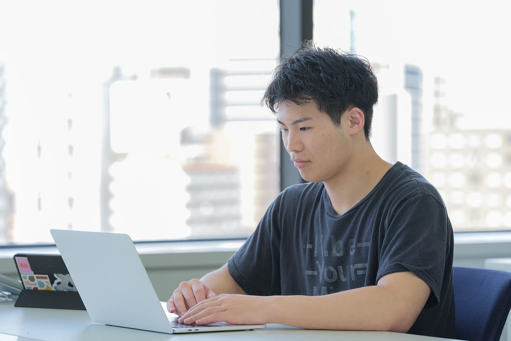 オフィスでノートPCに向かって作業する男性