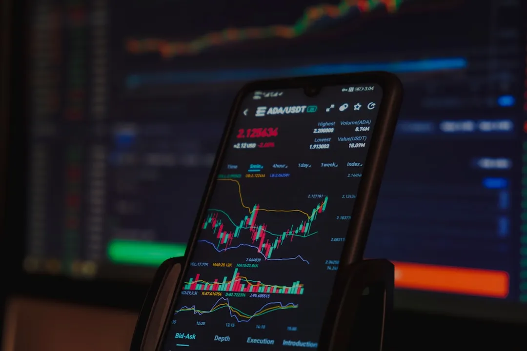 スマートフォンに表示された金融市場の取引チャートと分析データ