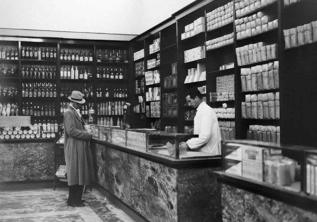 薬局の調剤カウンターと医薬品棚。多店舗の記録を紙で回す運用の限界を示すイメージ