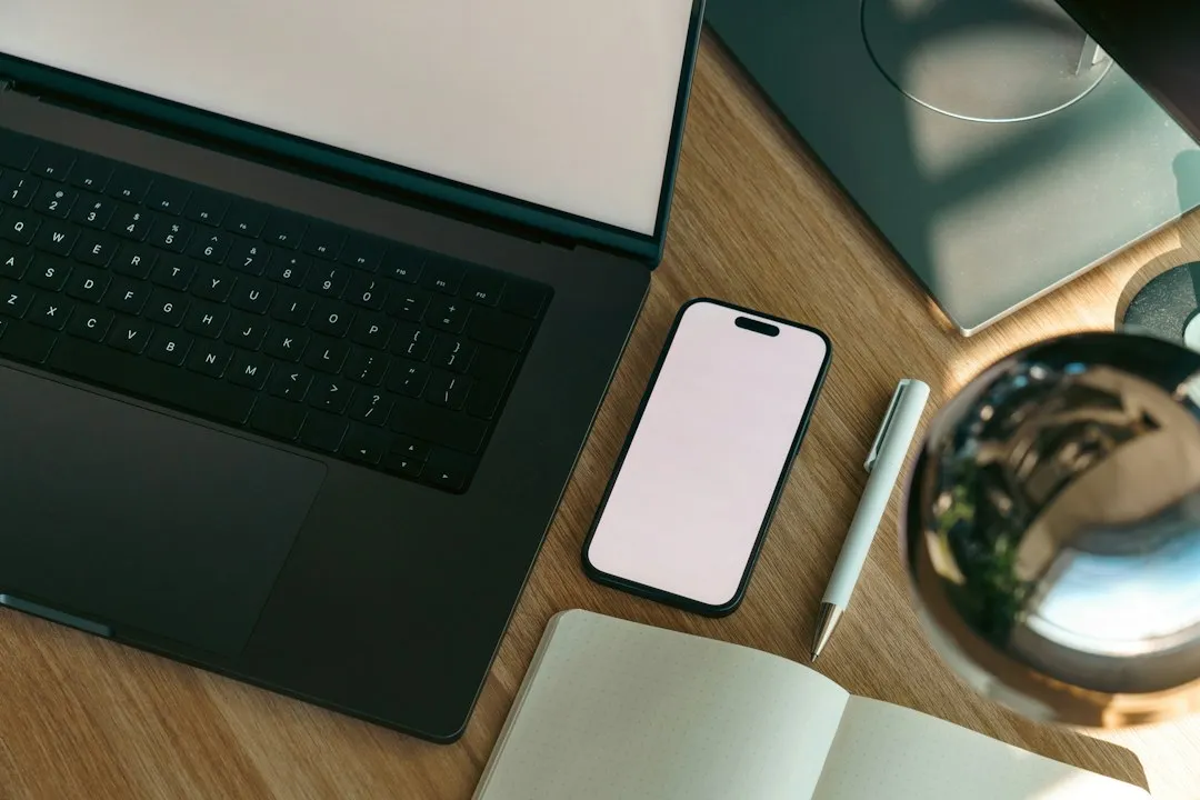 ノートパソコンとスマートフォンが置かれた仕事机