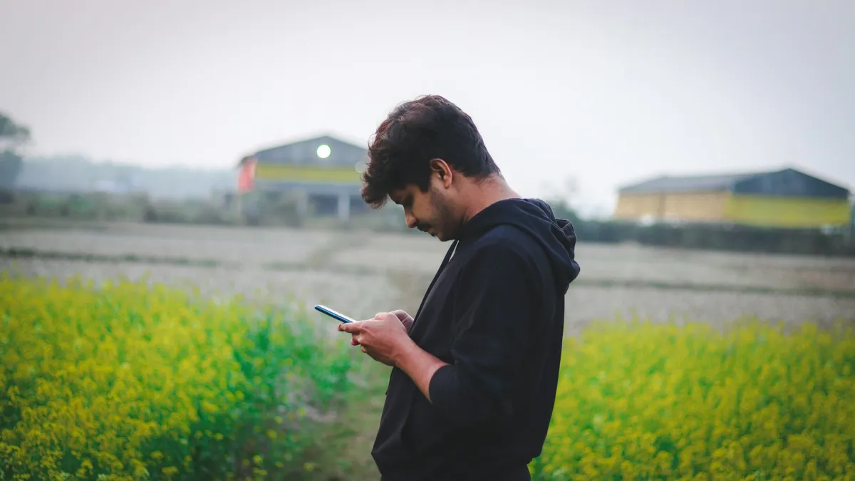 畑の中でスマートフォンを操作して作業を記録するイメージ