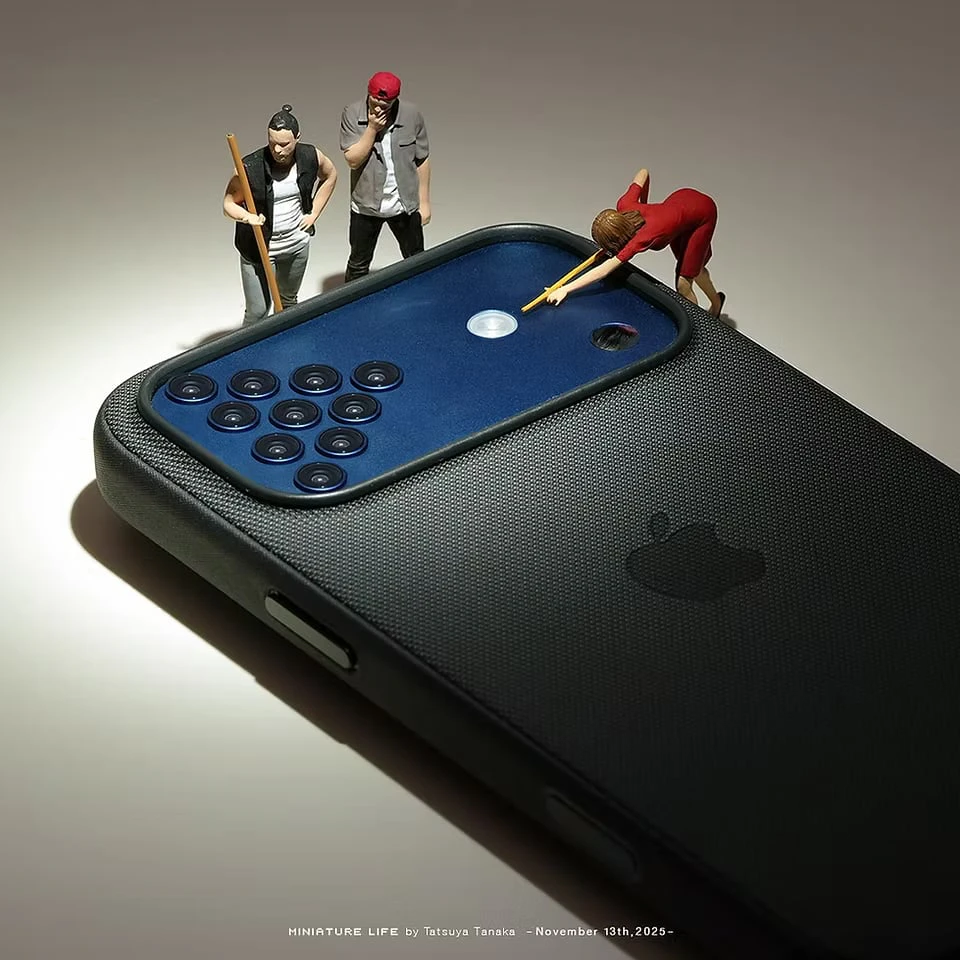 The camera module of a smartphone as a billiard table, its lenses racked like balls as tiny figures line up a shot