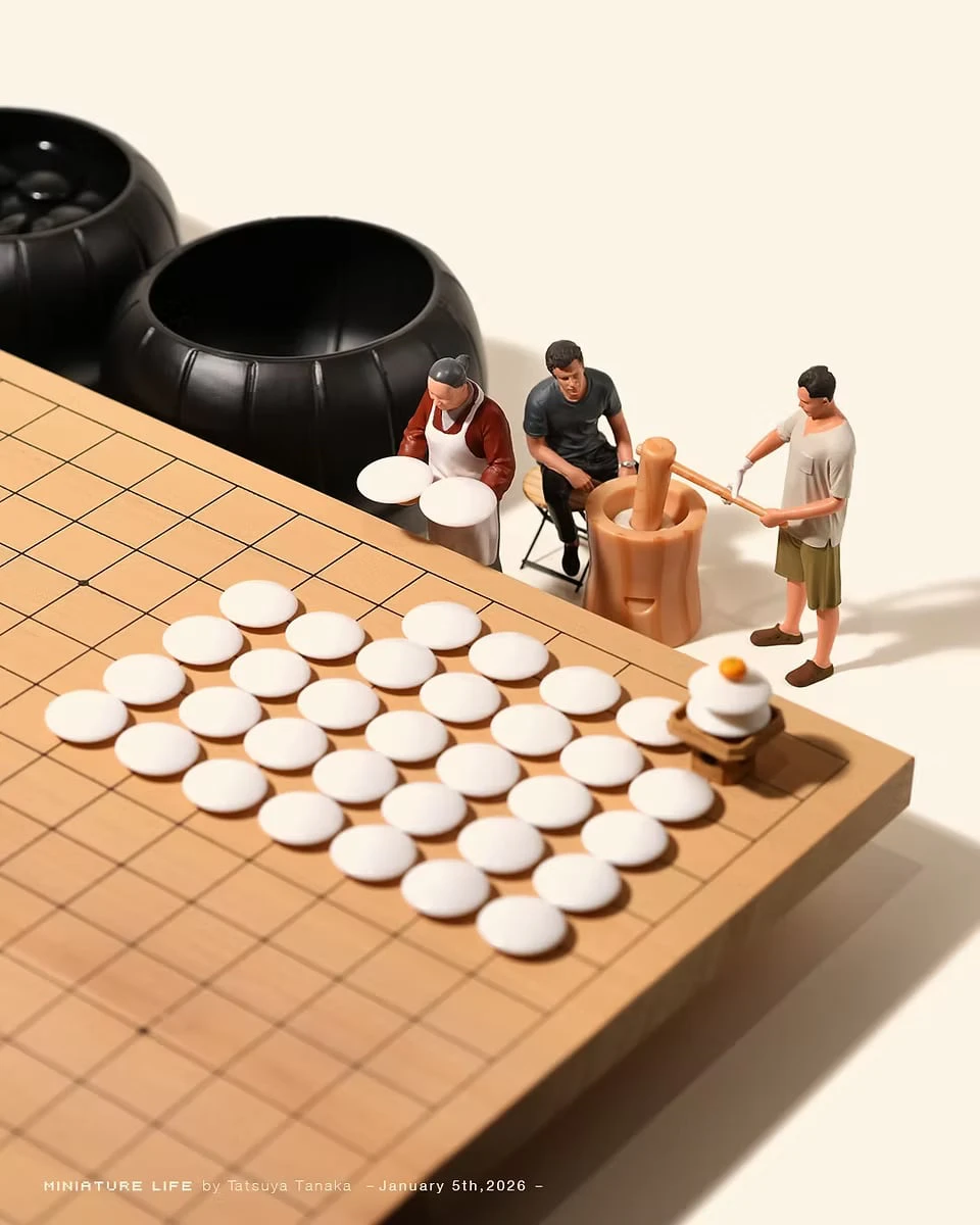 White go stones laid out on a go board as rice cakes, while figures pound mochi with a mortar and mallet beside a kagami mochi made of stacked stones