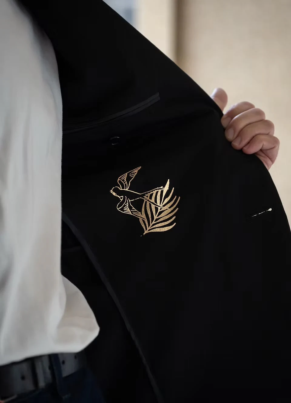 Close-up of a bird in flight and a leaf, drawn in gold on the black lining of a jacket