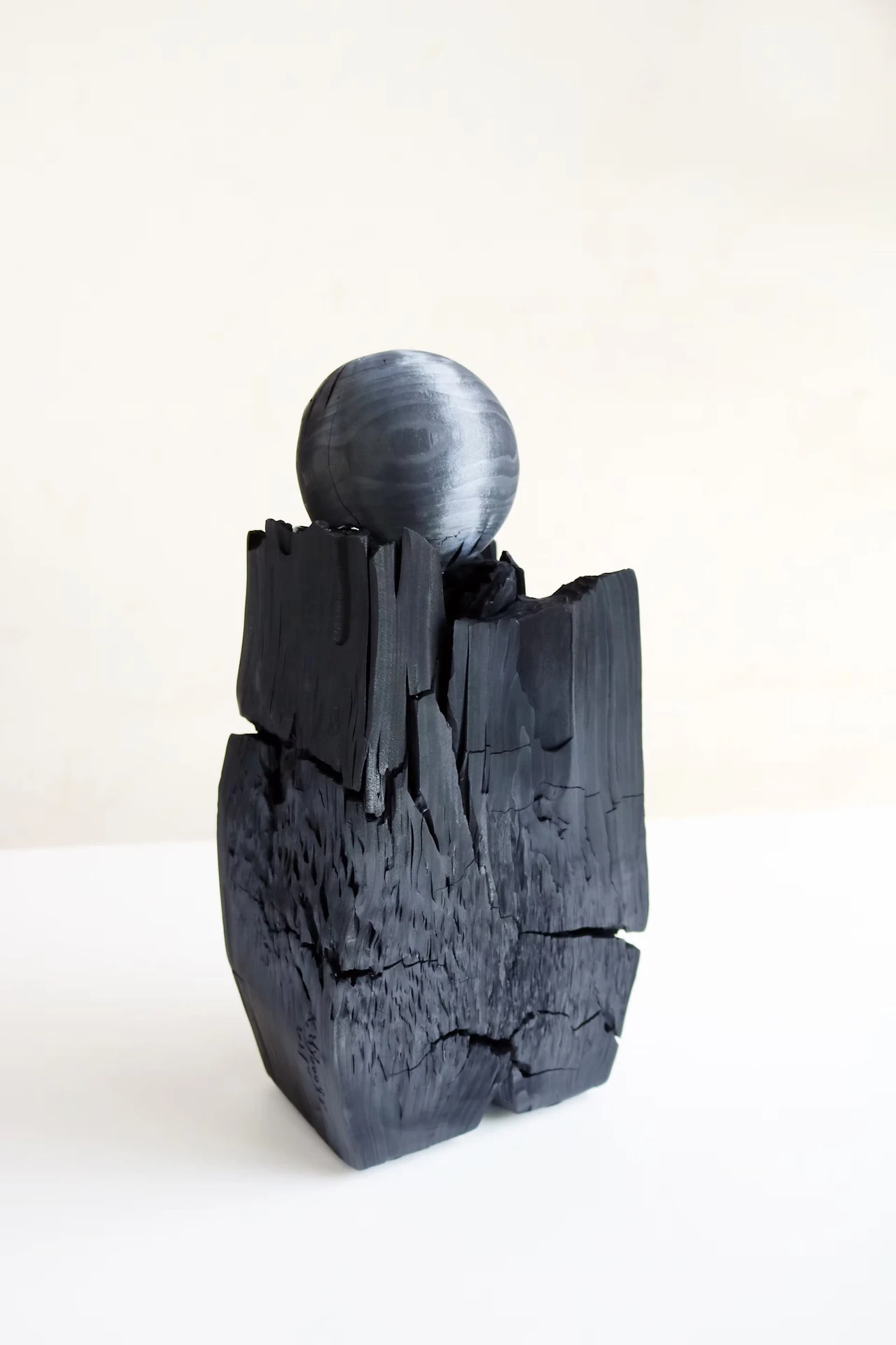 A black sphere resting on a cracked block of charcoal