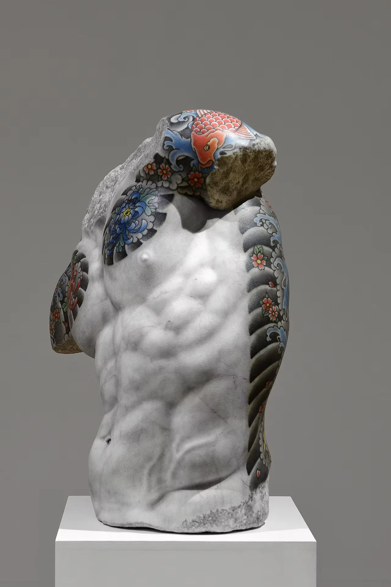 The same torso against a grey background, the carp, chrysanthemum and wave tattoos running right up to the rough broken edge