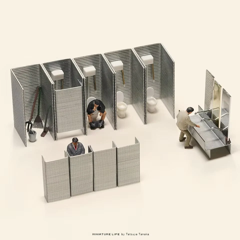 Strips of staples stood on end as the partitions of a public toilet, with tiny figures at the cubicles, urinals and washbasins