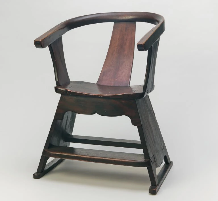 A dark-brown wooden armchair whose bent top rail curves round into the armrests