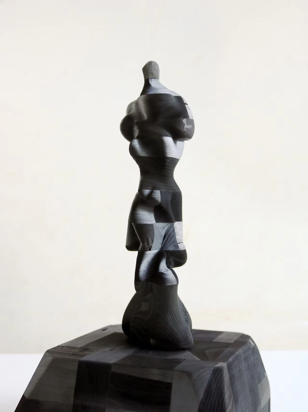 A slender sculpture carved into a chequered pattern, set on a faceted base