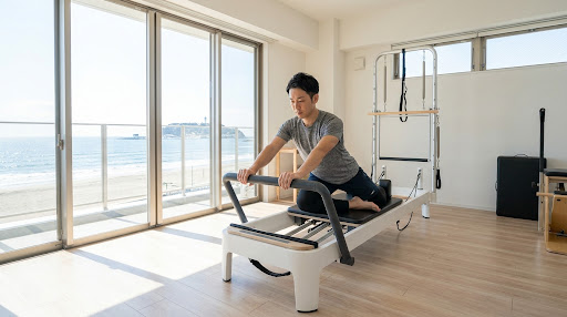 海が見える完全個室のリフォーマースタジオで、集中してトレーニングに取り組む男性