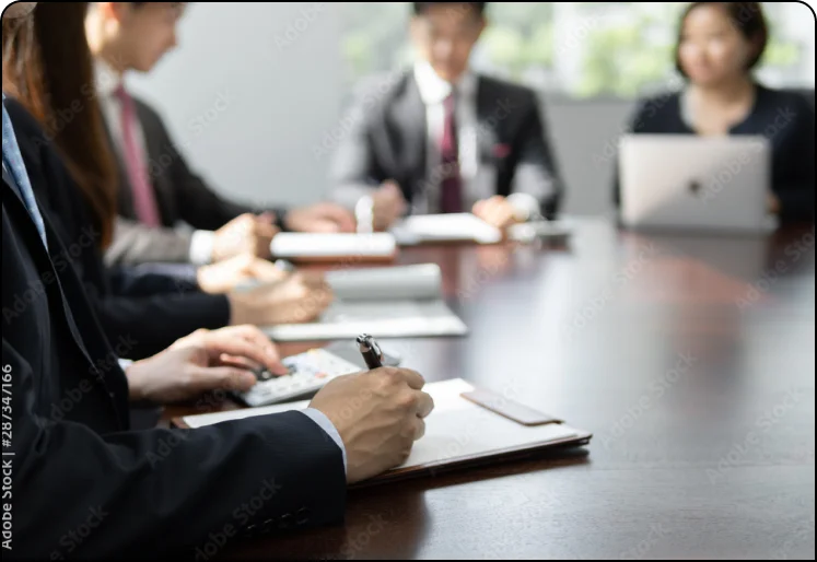 会議室で資料を見ながら話し合う人たち