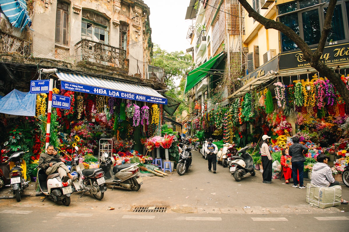 A group of people walking down a street next to parked motorcycles