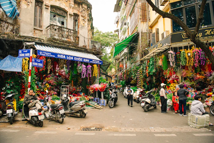 A group of people walking down a street next to parked motorcycles