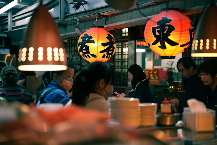 People sit at a restaurant with glowing lanterns overhead.