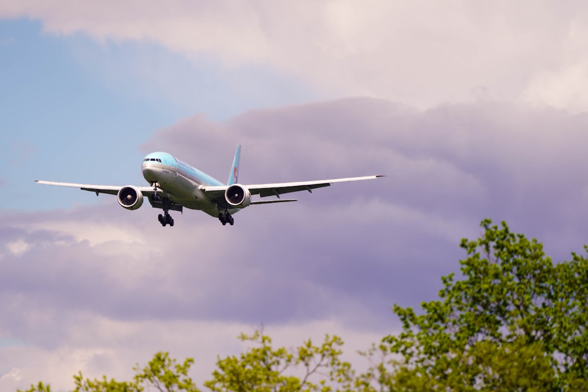 white and blue airplane flying under blue sky during daytime