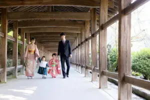 吉備津神社の回廊を、七五三の親子4人が手をつないで仲良く歩いている様子