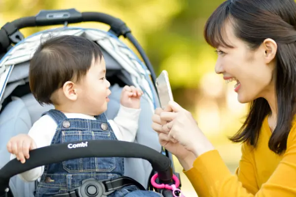 赤ちゃんをスマホ撮影する笑顔のママ