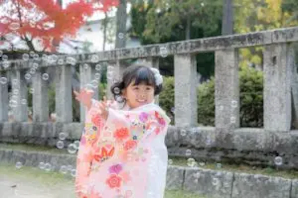 岡山県の吉備津彦神社の境内で、色とりどりのしゃぼん玉に両手を伸ばして笑う七五三の女の子