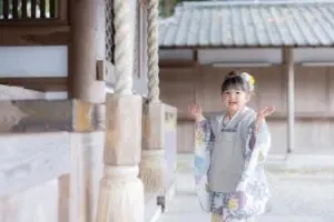 吉備津神社の木造回廊で、両手を広げてポーズを取る着物姿の女の子